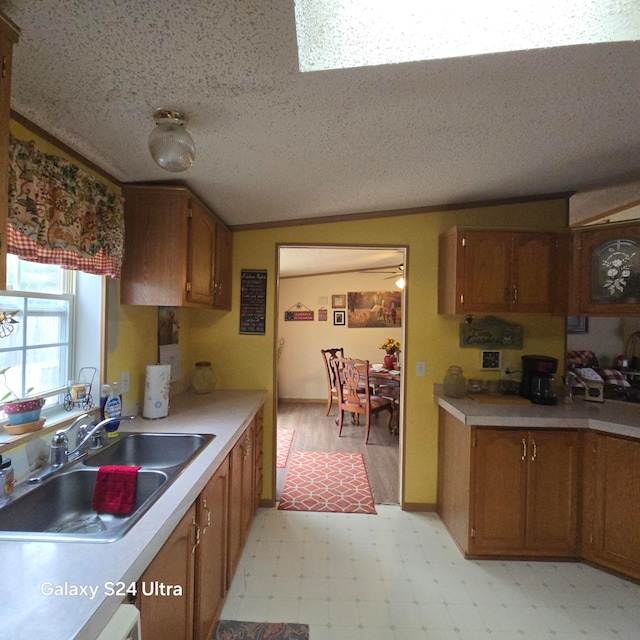 kitchen featuring light tile flooring, vaulted ceiling, a textured ceiling, and sink