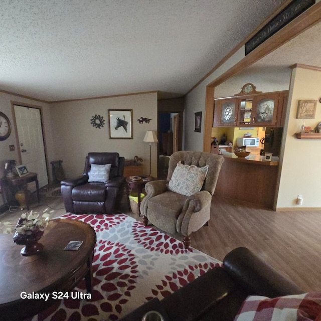 living room with a textured ceiling, wood-type flooring, and ornamental molding