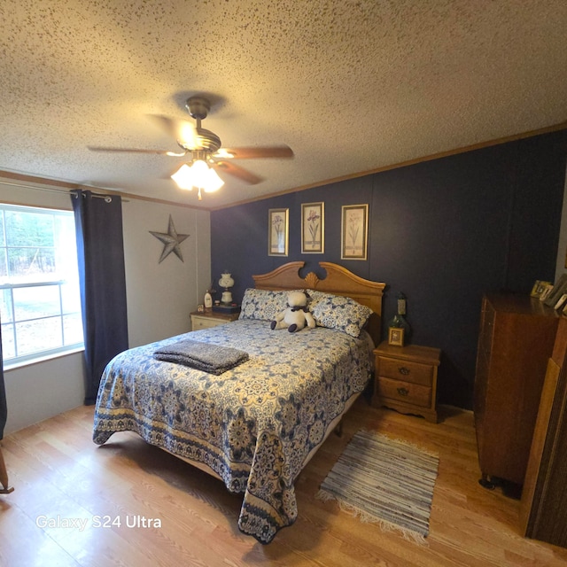 bedroom featuring light hardwood / wood-style flooring, ceiling fan, crown molding, and a textured ceiling