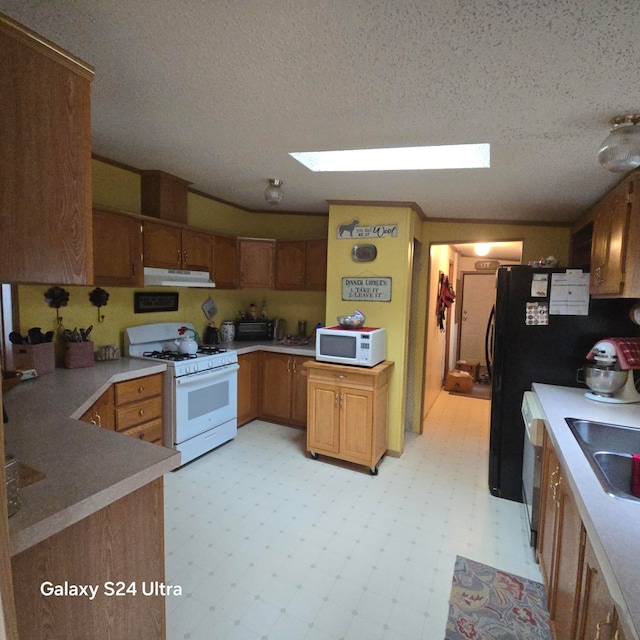 kitchen featuring light tile floors, a skylight, a textured ceiling, white appliances, and sink