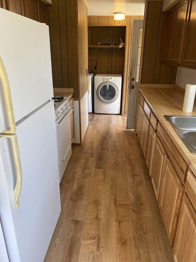 kitchen with hardwood / wood-style floors, sink, white appliances, and washer and clothes dryer