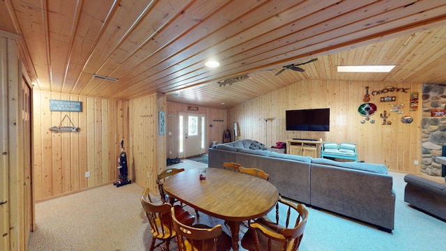 carpeted dining space with lofted ceiling with skylight, wooden ceiling, and ceiling fan