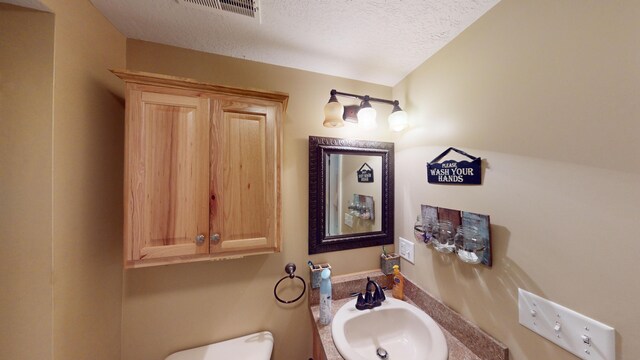 bathroom featuring toilet, sink, and a textured ceiling