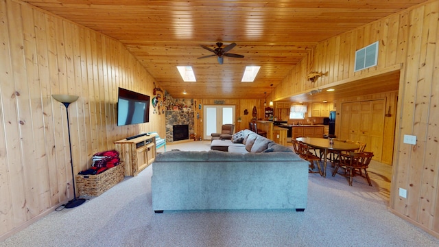 living room with wood ceiling, lofted ceiling with skylight, ceiling fan, and light colored carpet