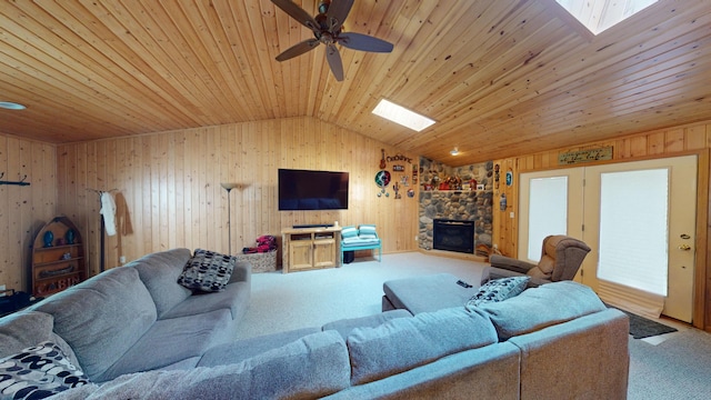 living room with wood ceiling, a fireplace, vaulted ceiling with skylight, carpet flooring, and ceiling fan