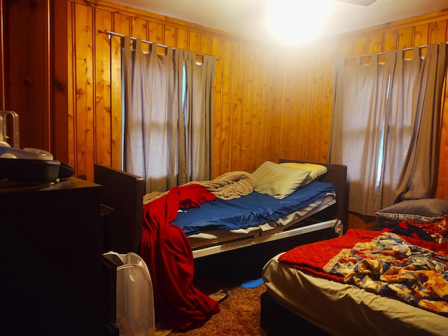 carpeted bedroom featuring wood walls