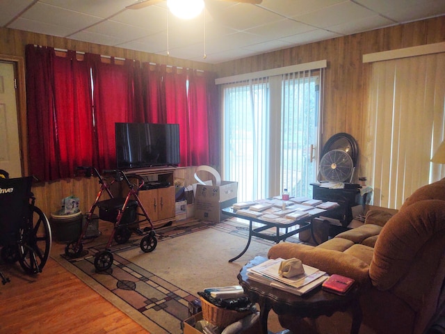 living room featuring wooden walls, ceiling fan, and hardwood / wood-style floors