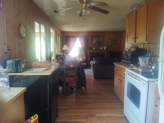 kitchen featuring wooden walls, white electric stove, ceiling fan, and light wood-type flooring