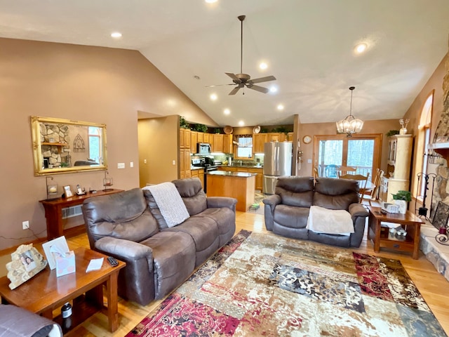 living room with high vaulted ceiling, light wood-type flooring, and ceiling fan with notable chandelier