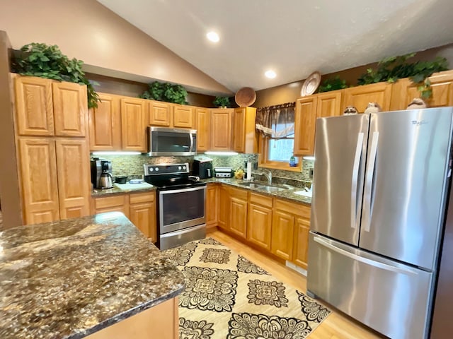 kitchen featuring lofted ceiling, backsplash, dark stone countertops, and stainless steel appliances