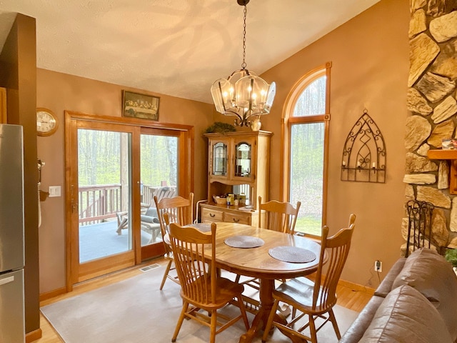 dining space featuring a chandelier, light hardwood / wood-style flooring, and a textured ceiling