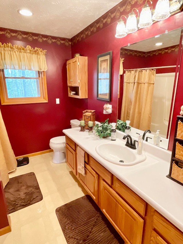 bathroom with tile floors, vanity with extensive cabinet space, a textured ceiling, and toilet