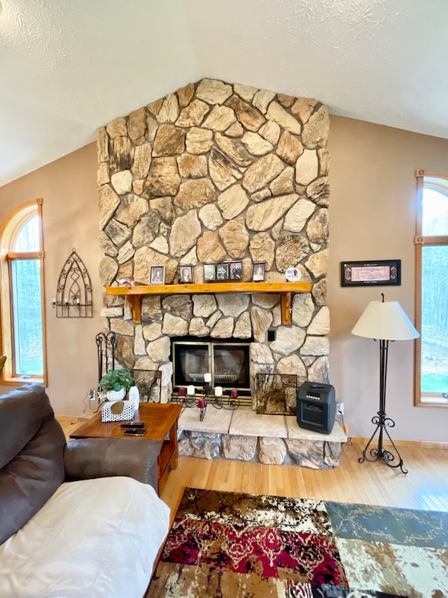 living room featuring a healthy amount of sunlight, wood-type flooring, a fireplace, and vaulted ceiling