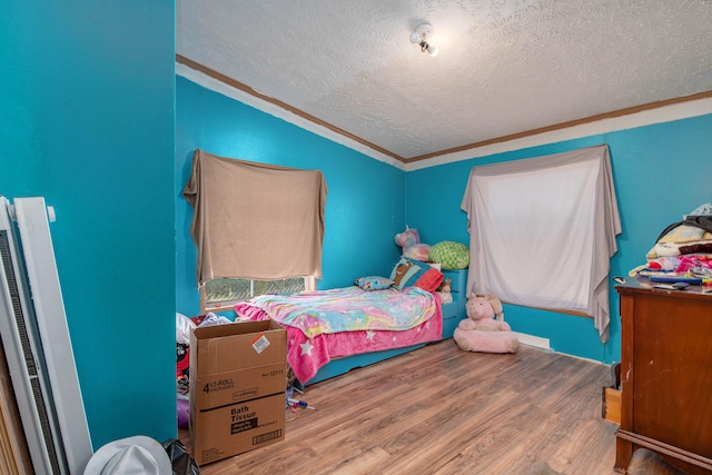 bedroom with crown molding, hardwood / wood-style flooring, and a textured ceiling