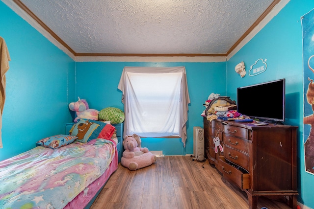 bedroom with hardwood / wood-style flooring, a textured ceiling, and crown molding