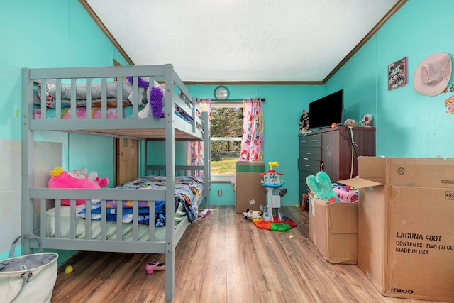 bedroom with a textured ceiling, ornamental molding, and hardwood / wood-style floors