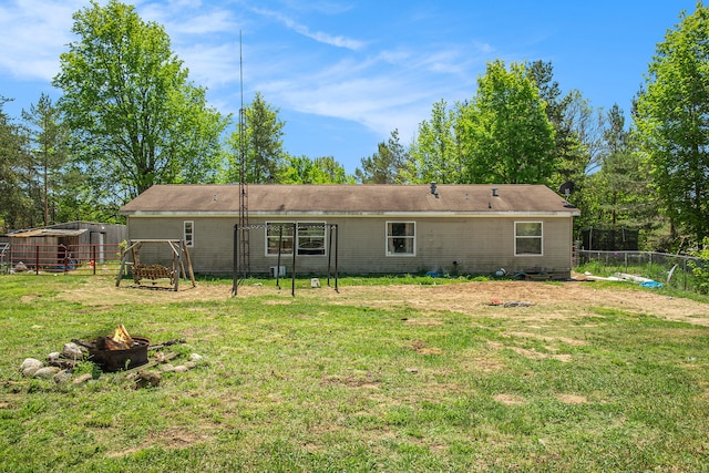 back of property with a fire pit and a lawn