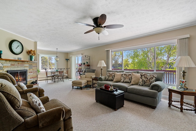 carpeted living room featuring a textured ceiling, plenty of natural light, ceiling fan, and a fireplace