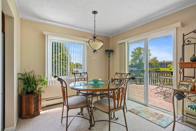 dining space with a baseboard heating unit, crown molding, and carpet flooring