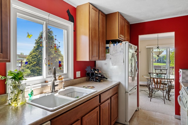 kitchen featuring sink, white fridge, light tile flooring, and hanging light fixtures