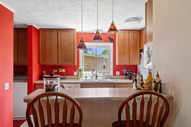 kitchen featuring hanging light fixtures, sink, a textured ceiling, and washer / clothes dryer