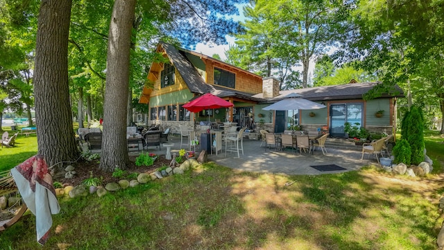 back of house with a patio and a lawn