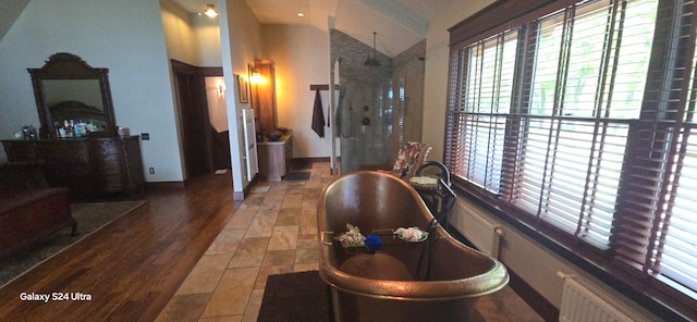 bathroom featuring a shower with door, lofted ceiling, radiator heating unit, and wood-type flooring