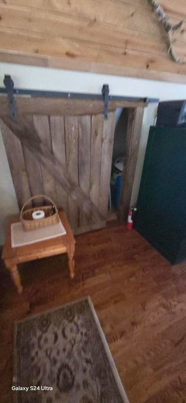 room details featuring a barn door, wooden walls, and wood-type flooring