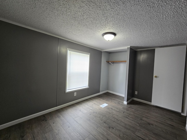 unfurnished bedroom featuring dark hardwood / wood-style floors, a textured ceiling, and a closet