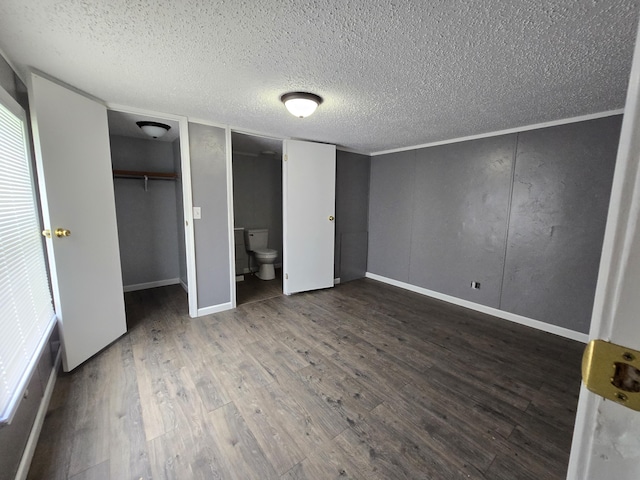 unfurnished bedroom with hardwood / wood-style flooring, ensuite bathroom, and a textured ceiling