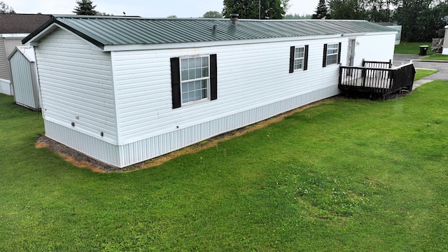 view of side of home featuring a yard and a wooden deck