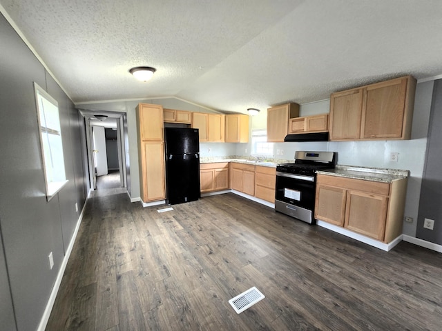 kitchen featuring black fridge, stainless steel gas stove, dark hardwood / wood-style floors, and lofted ceiling