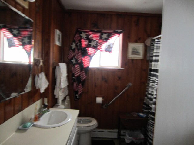 bathroom featuring a baseboard heating unit, wood walls, large vanity, and toilet