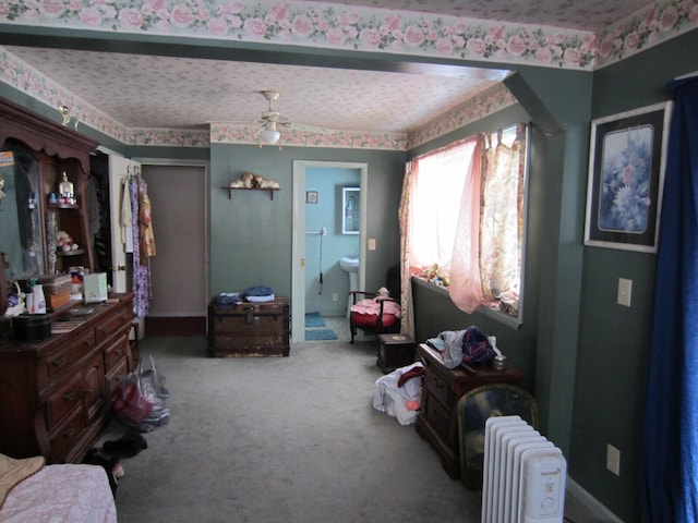 carpeted bedroom with a textured ceiling, ensuite bath, ceiling fan, and radiator