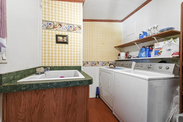 clothes washing area with hardwood / wood-style floors, crown molding, sink, a textured ceiling, and washing machine and clothes dryer