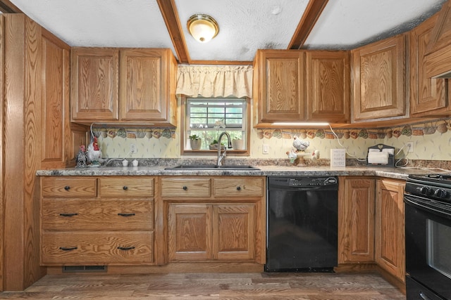 kitchen featuring beam ceiling, sink, dark hardwood / wood-style flooring, dark stone countertops, and black appliances