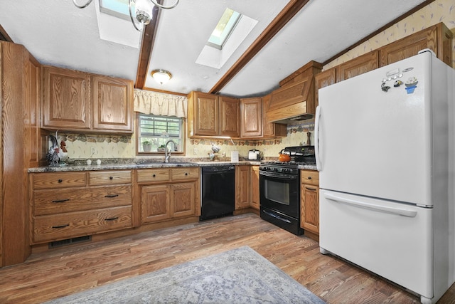 kitchen featuring vaulted ceiling with skylight, sink, black appliances, and light hardwood / wood-style floors