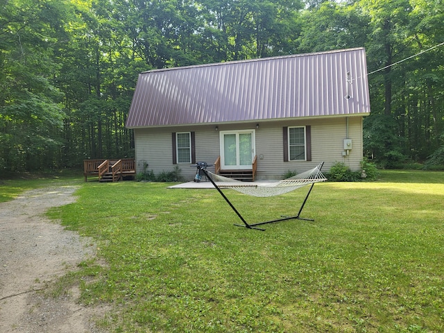 rear view of property featuring a deck, a lawn, and a patio