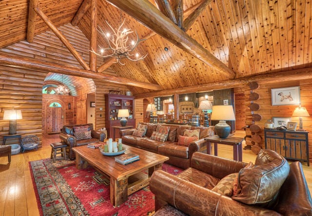 living room with high vaulted ceiling, hardwood / wood-style flooring, rustic walls, and wooden ceiling