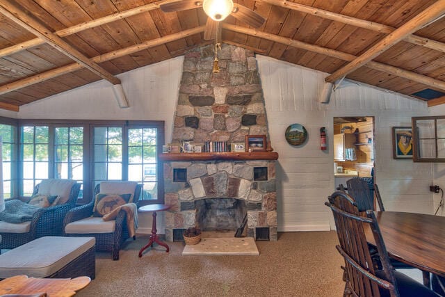 carpeted living room with ceiling fan, lofted ceiling with beams, a fireplace, and wooden ceiling