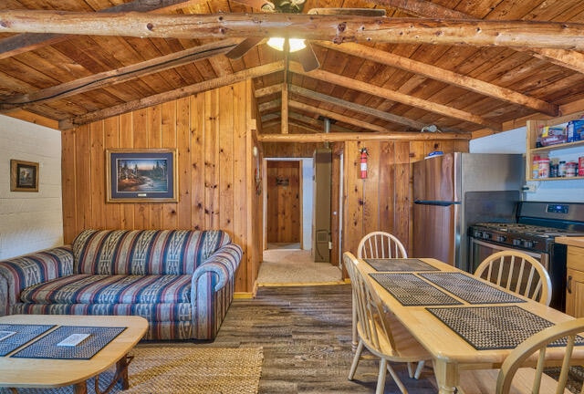 dining space with wooden ceiling, hardwood / wood-style flooring, vaulted ceiling with beams, and wood walls