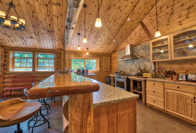 kitchen featuring wooden ceiling, high end stove, wall chimney exhaust hood, decorative light fixtures, and high vaulted ceiling