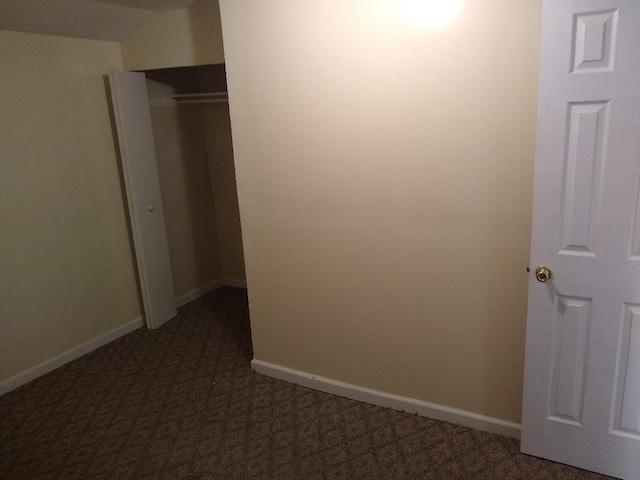 unfurnished bedroom with a closet and dark colored carpet