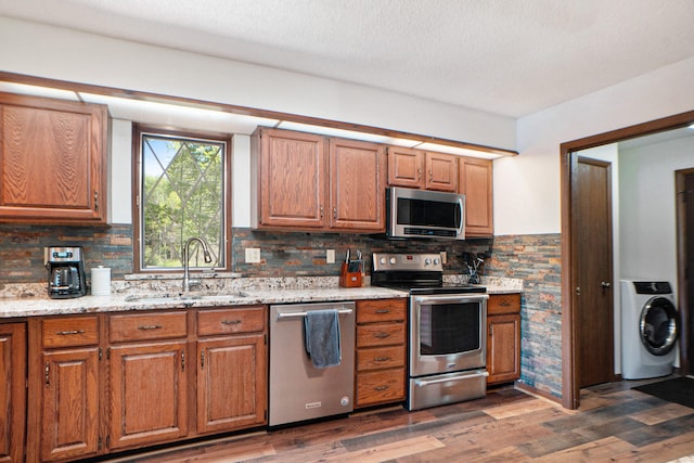 kitchen featuring stainless steel appliances, washer / dryer, tasteful backsplash, and dark wood-type flooring