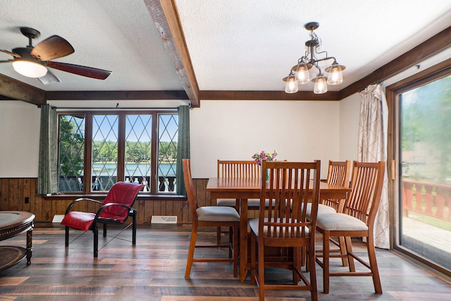 dining area with dark wood-type flooring, a textured ceiling, ceiling fan with notable chandelier, and a wealth of natural light