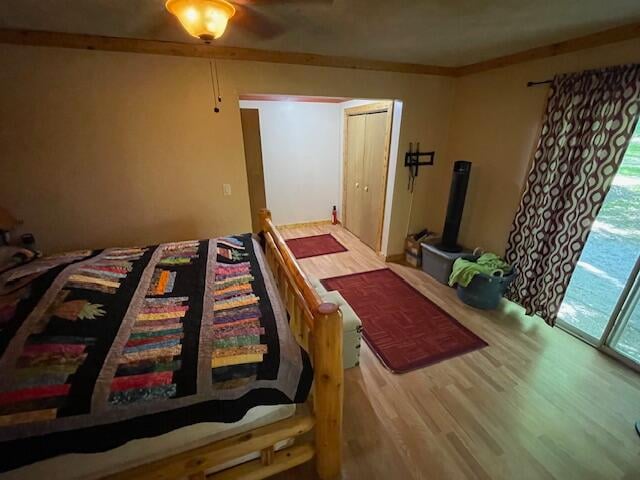 bedroom with ornamental molding, a wood stove, hardwood / wood-style flooring, and access to exterior