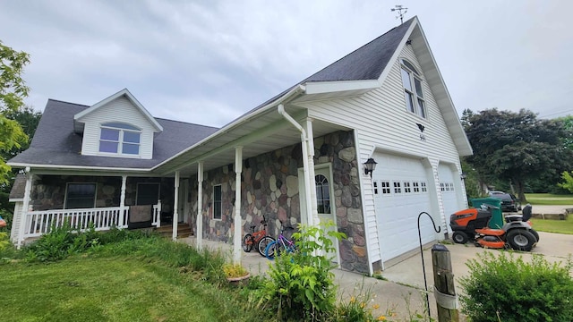 view of front of home featuring a porch, a garage, and a front lawn