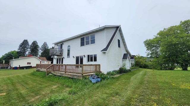 back of house featuring a balcony, a lawn, and a wooden deck