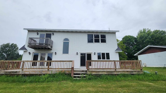 back of house with a balcony, a wooden deck, and a lawn