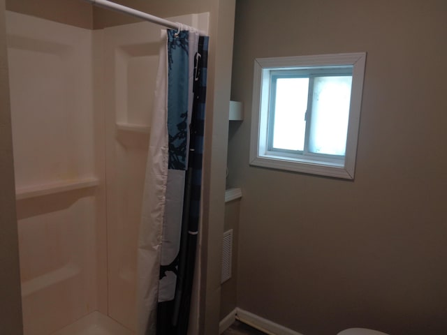 bathroom featuring a shower with shower curtain and toilet